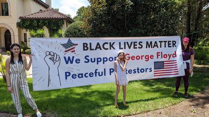 Don and Anna Juravin's daughters pose with a yard sign the couple put in their yard in Bella Collina to teach their children about American values, civil rights and the importance of participating and protesting. (Don Juravin)